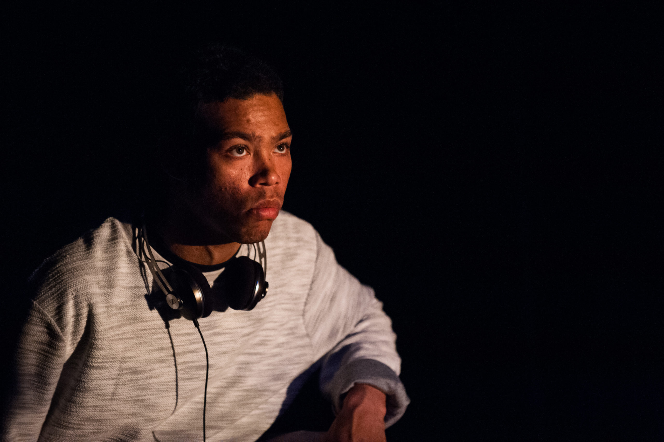 A young black man stares with a look of concentration on his face.