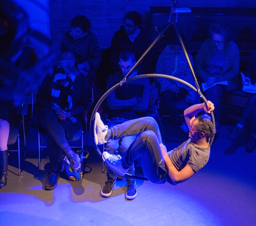 A young boy sits on an aerial hoop