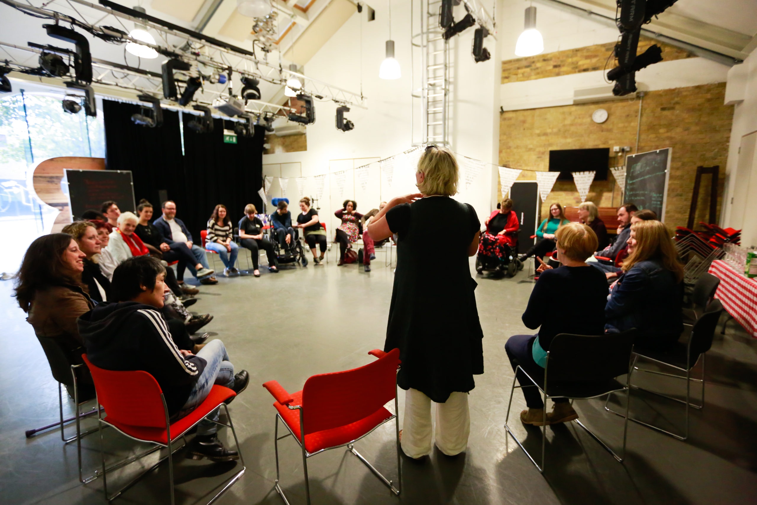 A group of people in a circle of chairs in Graeae's rehearsal room