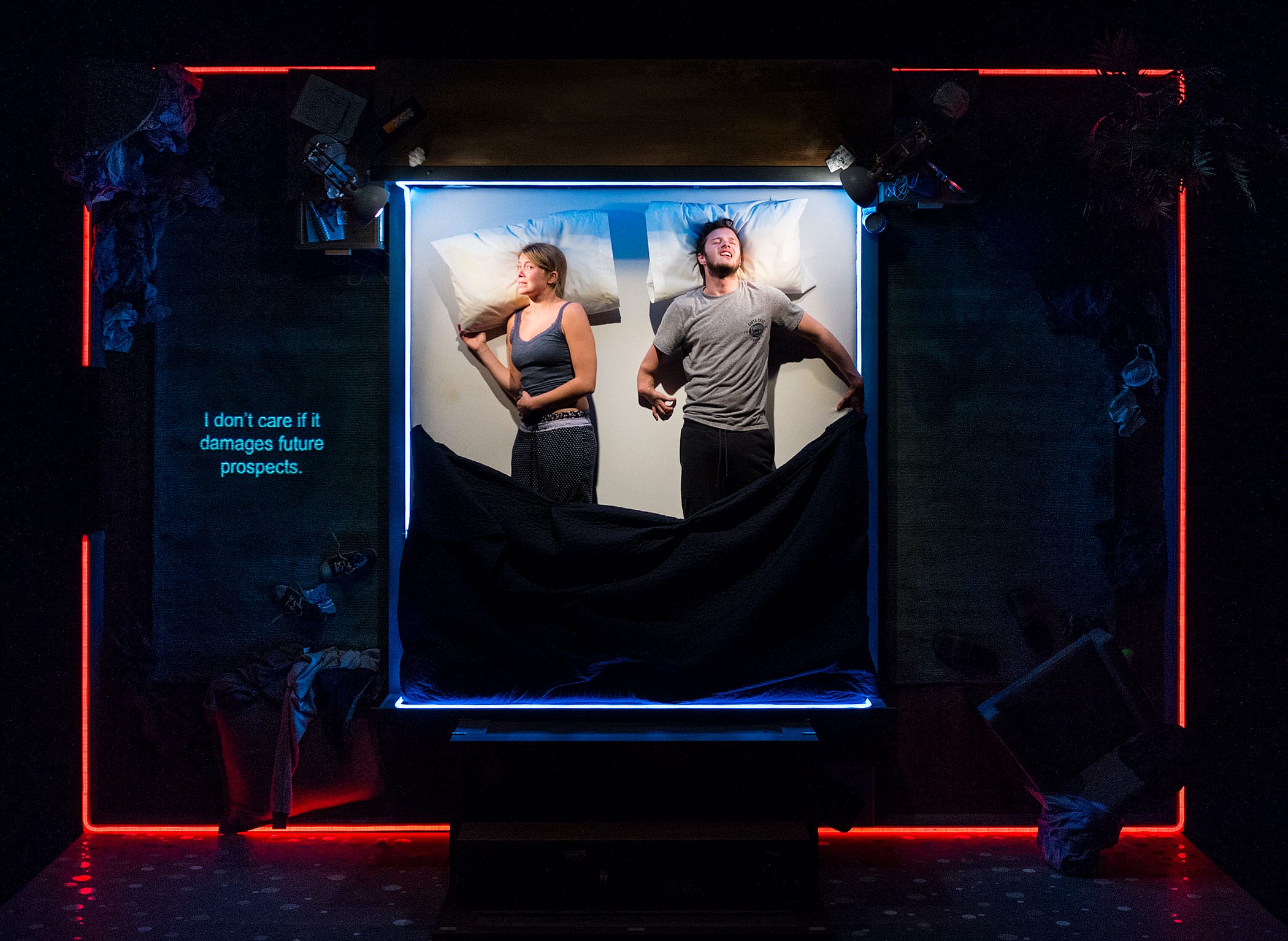 a picture of Genevieve Barr & Arthur Hughes on stage in the vertical bed set of The Solid Life of Sugar Water'. The performers are in bed together, facing away from each other.