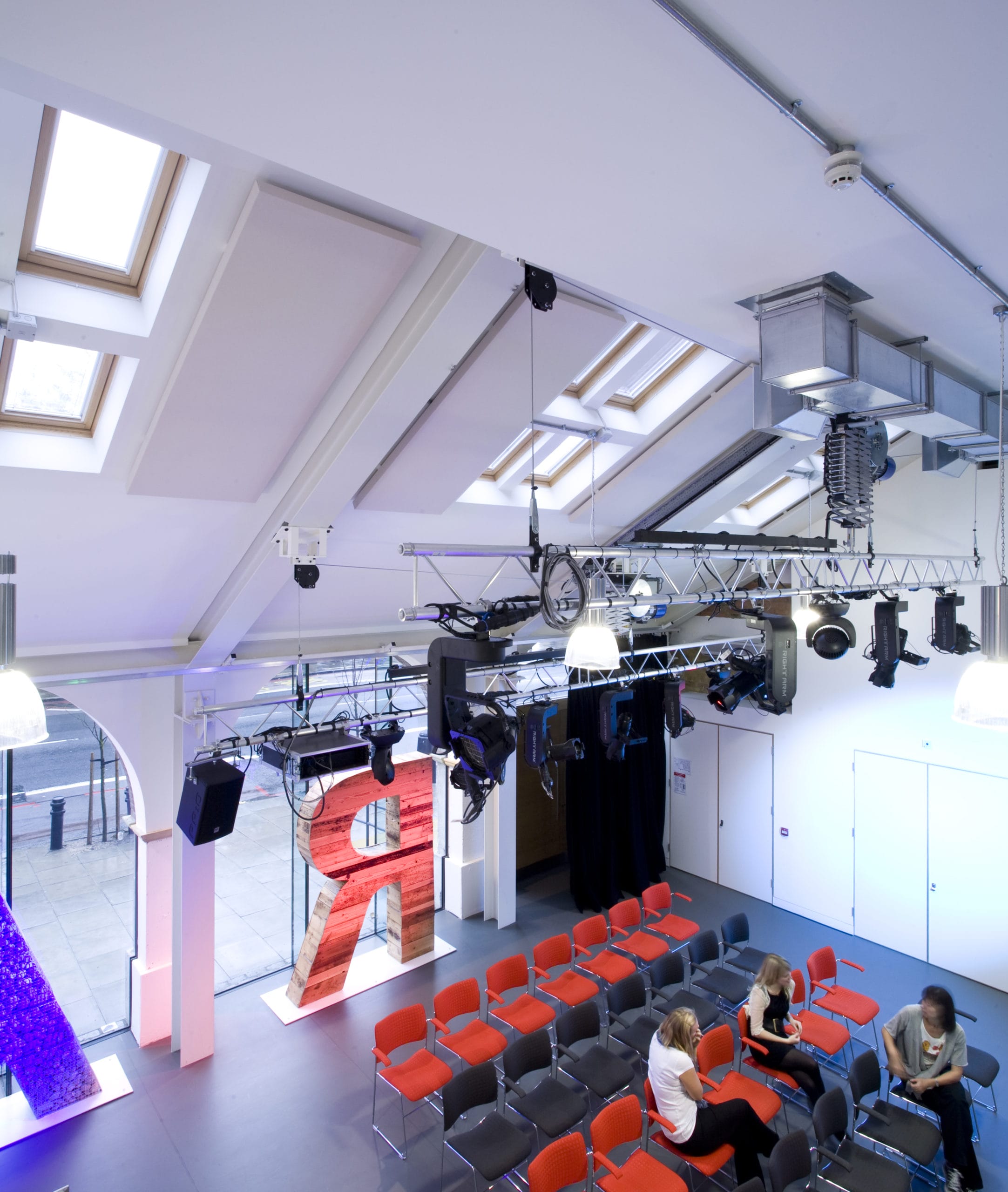 Graeae's rehearsal room, taken from above, with rows of red and black chairs laid out.