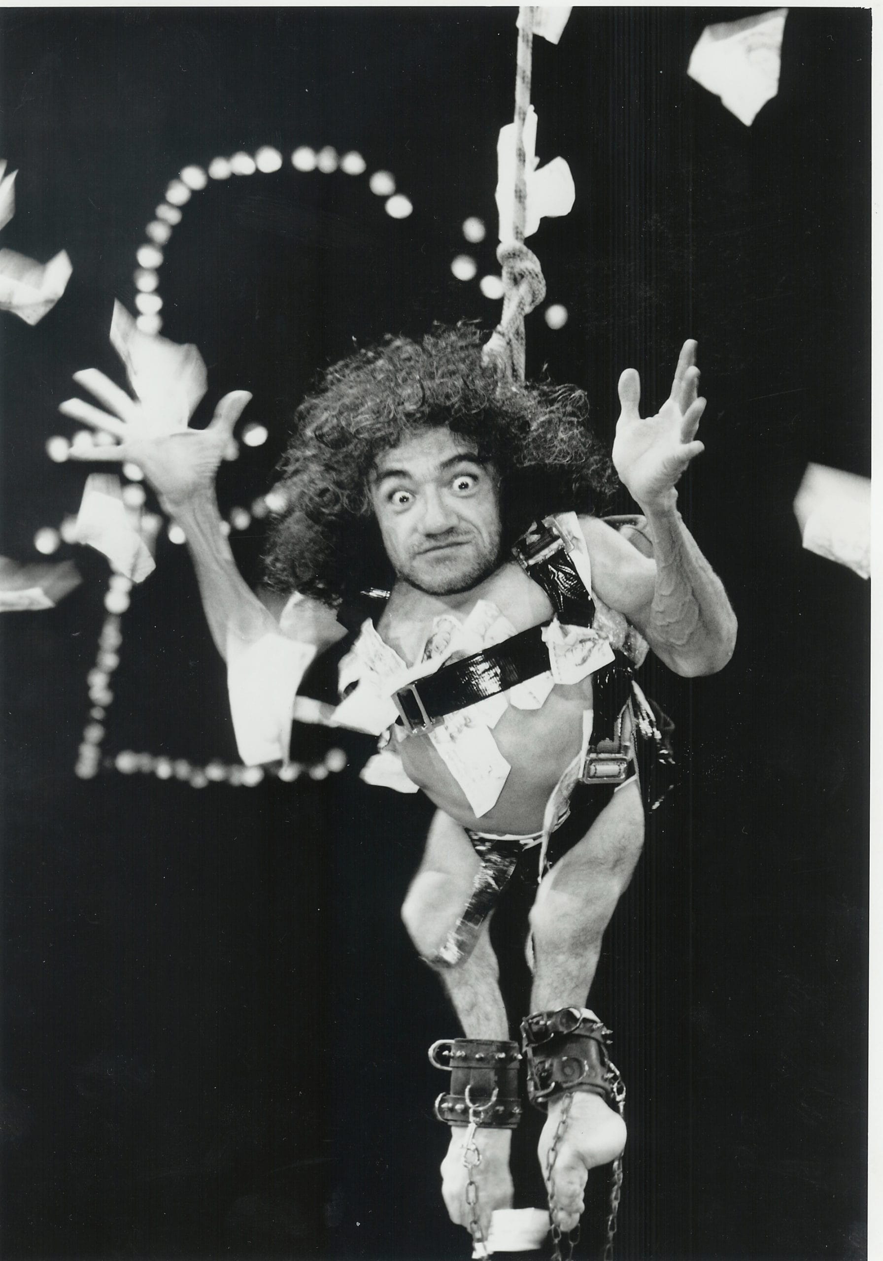 Nabil Shaban is suspended above the stage wearing nothing but a harness. He shoots the camera a wild look.