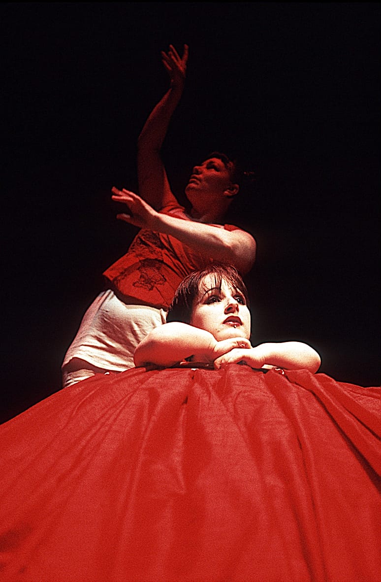 Two performers dressed in red and white costumes, strike dramatic poses.