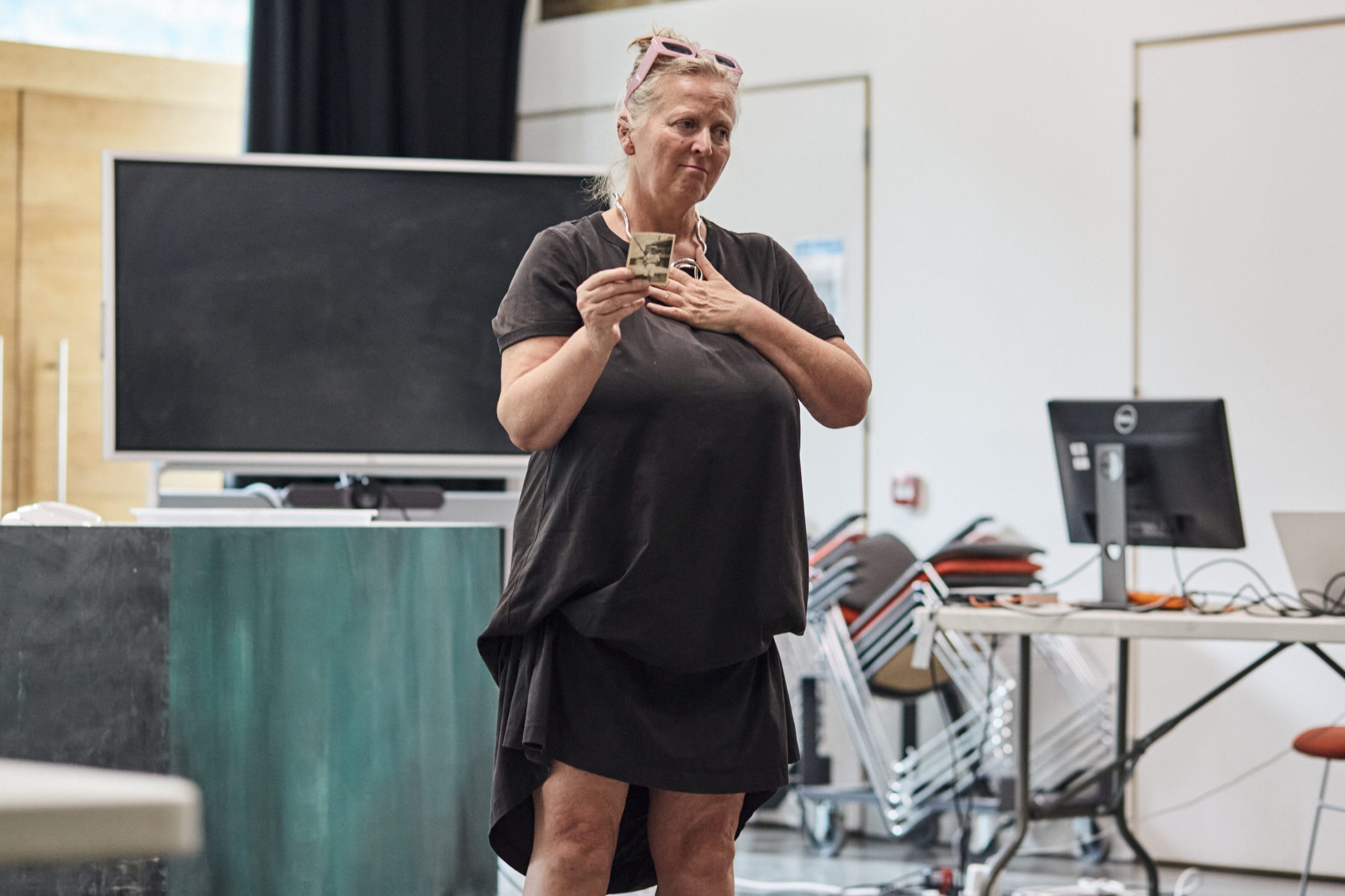 Jenny Sealey in rehearsal, she is holding a picture in one hand and clutching her chest with the other.