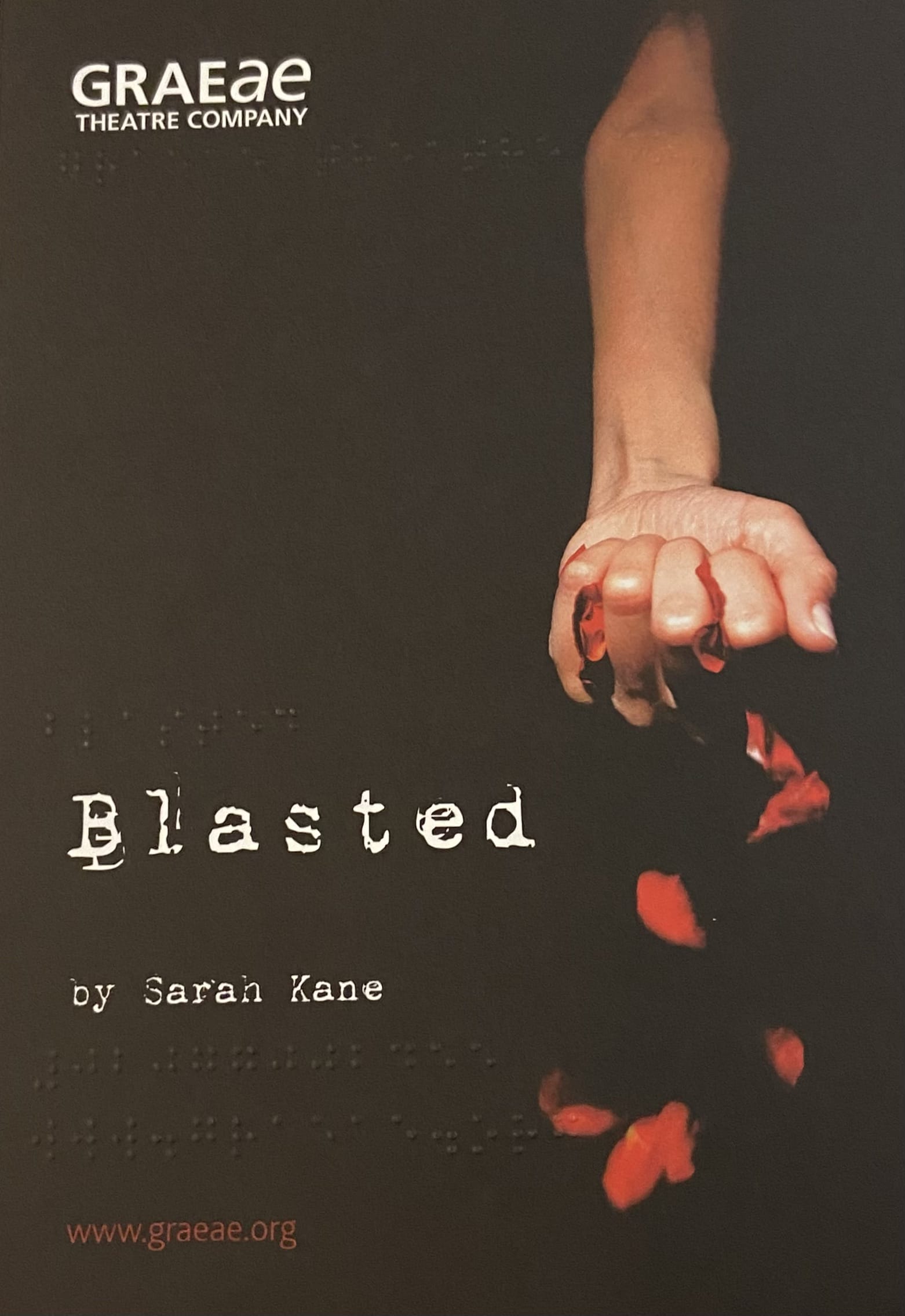 A poster for Graeae's production of 'Blasted' by Sarah Kane. The poster is black and title is written in a white type writer font. There is a hand clenched into a fist, with rose petals overflowing from its grasp.