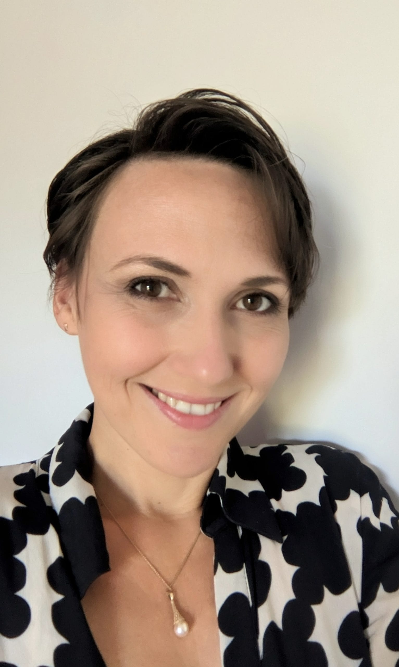 Headshot of a woman with short hair, she is smiling.