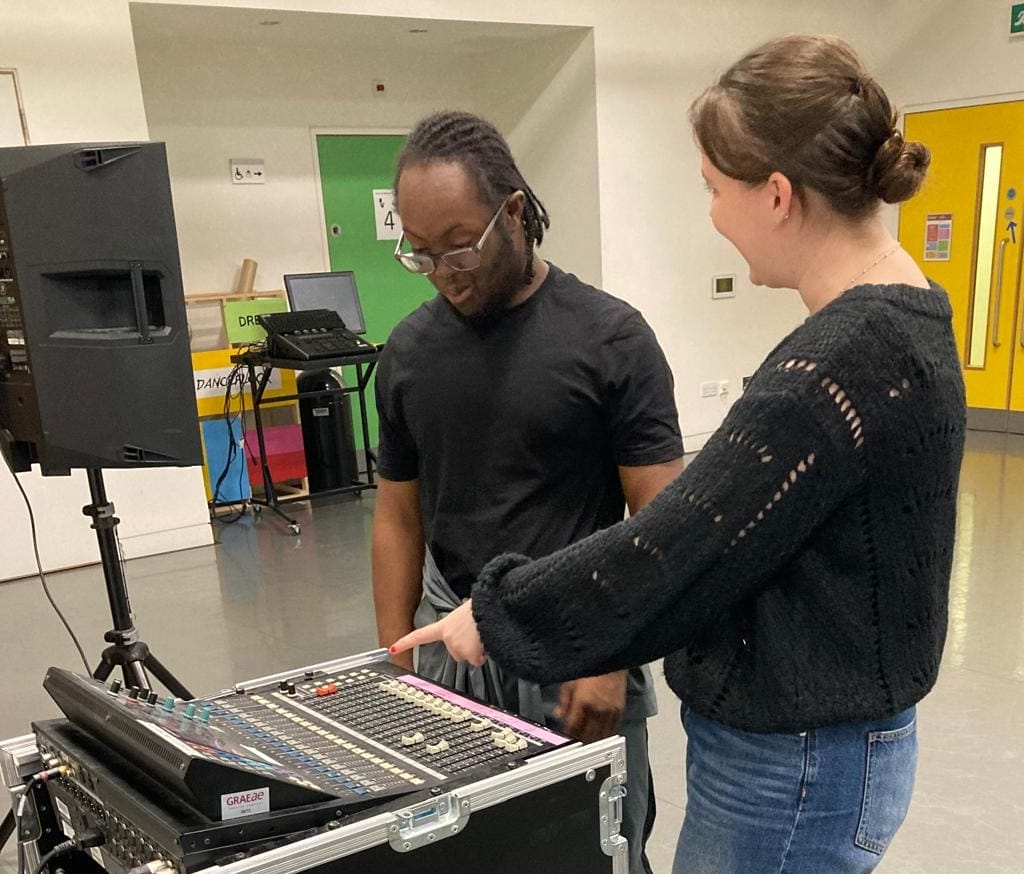 Marcus and Bridget are standing at a soundboard in the Graeae rehearsal room.