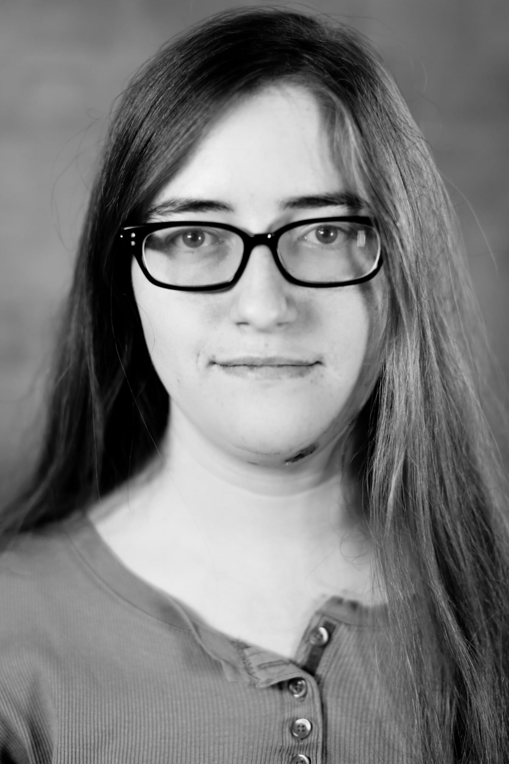 A white woman with long hair and rectangular glasses.