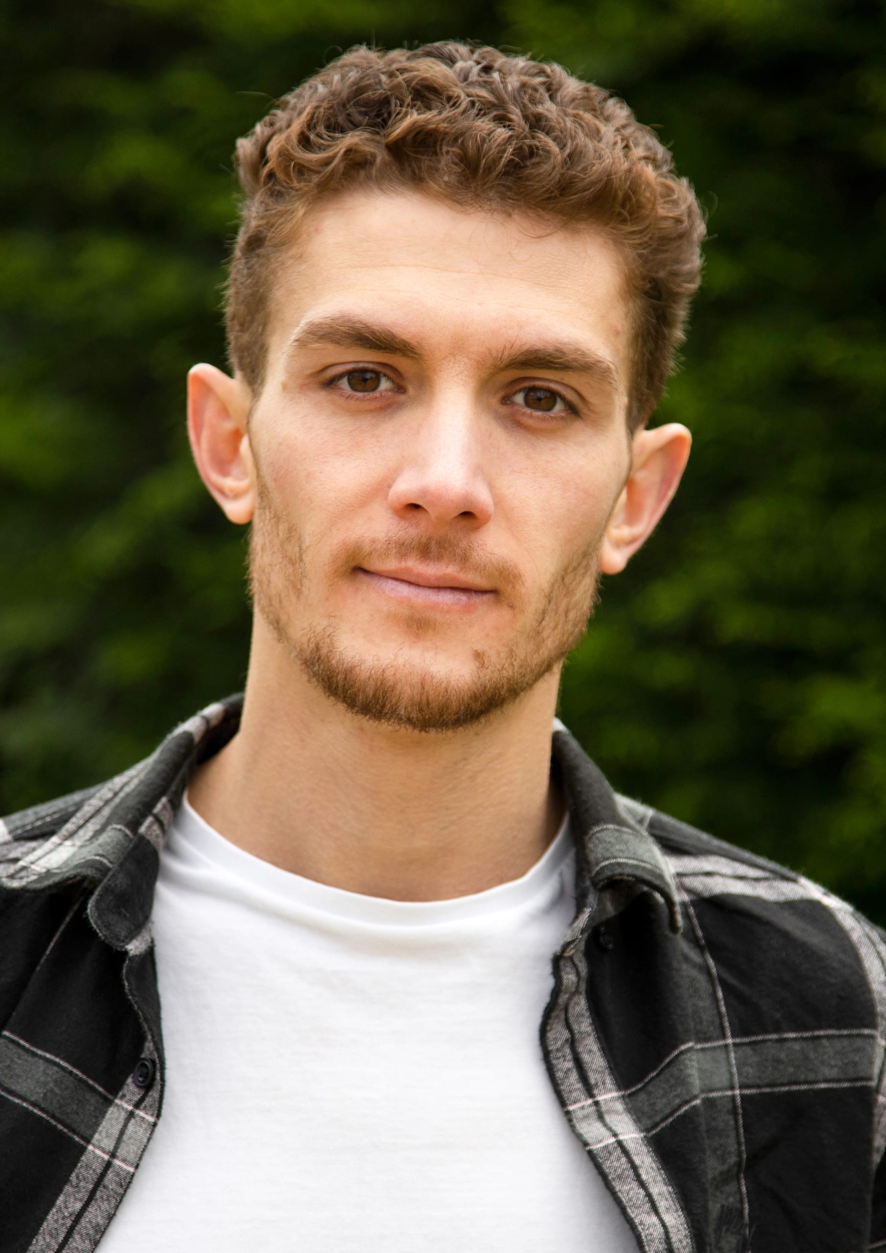 A white man with short curly brown hair..