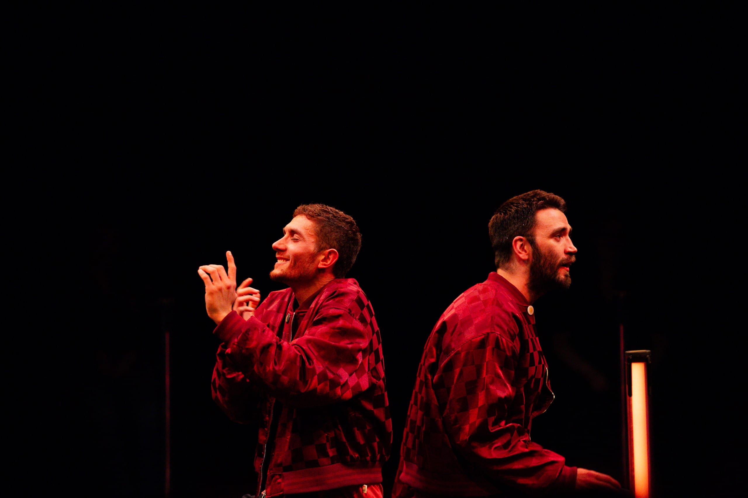 Petre and Ciaran back to back. They are both in red checked jackets. They look out to the audience longingly.