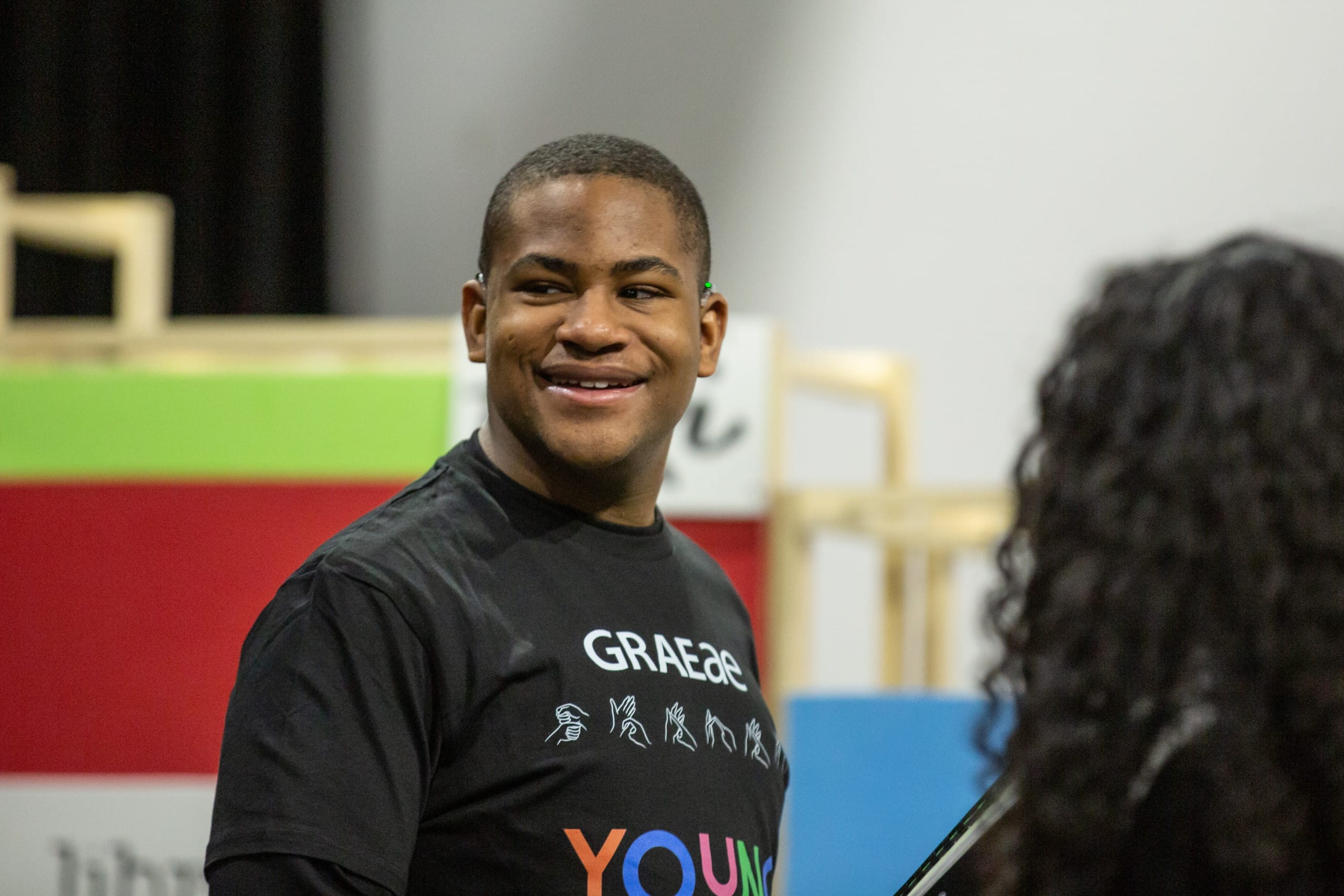 Headshot of Josiah wearing a black t-shirt with grey eye on